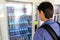 Young male backpacker tourist choosing a snack or drink at vending machine. Vending machine with man