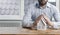 A young male businessman holds his hands over a miniature paper house. The concept of protection and security of property and home