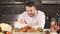 Young male chef presents his special dish. He stands in a big restaurant kitchen