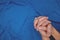 Young male closed hands praying top view in dark blue background.