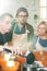 Young male cooking coach and his two trainees in aprons bending over workplace