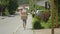 Young male courier leisurely strolls along the sidewalk carrying big packages.