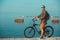 Young Male Cyclist With Bicycle Walking On Coast And Enjoying View Of Sea. Holiday Travel Activity Concept