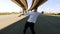 Young male dancer in hat and striped t-shirt dancing under the bridge, goes to the camera