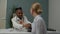 Young male doctor checking blood pressure to female patient indoors