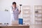 Young male doctor holding plunger in funny concept