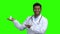 Young male doctor presenting pills on green screen.