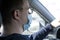 a young male driver is sitting in a car wearing a medical mask. view from the back seat of the car. self-defense against the virus