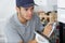 Young male electrician writing on clipboard while looking at oven