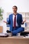 Young male employee doing yoga exercises during break