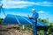 Young male engineer with laptop in hand standing near solar panels, agriculture farm land with clear blue sky background,
