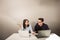 Young male and female business partners sitting behind a computer monitor and thinking of something