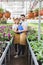 Young male and female owners of glasshouse holding clipboards