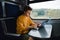 Young male freelancer in orange sweatshirt working on laptop in train with serious face. Work on vacation