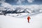 Young male freerider guide in a yellow ski suit with a backpack on his shoulders climbing the mountain on skis on a