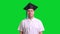 Young male graduate in black hat on green chroma key background
