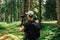 Young male hiker in casual clothes stands in a mountain forest with a camera on a stabilizer and makes a video. Video operator