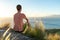 Young male hiker sitting on the summit of Diamond Head Crater in Honolulu, Oahu, Hawaii, looking down to Waikiki Beach and the cit