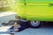 Young male hipster lying beneath his old timer camper van trying to repair it beside road