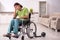 Young male invalid in wheel-chair suffering at home