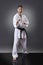 Young male karate doing kata on the gray background