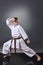 Young male karate doing kata on the gray background