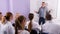 Young male lecturer answering near whiteboard in auditorium