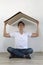 Young male in new empty room with carton cardboard over his head making as roof. Handsome attractive male sitting on floor