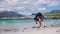 Young male photographer with dreadlocks at a sunny white sand beach,