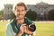 Young male photographer holding professional camera on street.