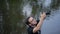 Young male photographer is standing in water working with camera.