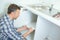 Young male plumber lying on floor fixing sink in bathroom