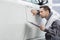 Young male repair worker examining car in automobile repair shop