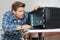 Young male repairman fixing oven in kitchen