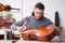 Young male repairman repairing cello