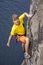 Young male rock climber hanging over the water