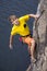 Young male rock climber hanging over the water