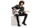 Young male rocker in a leather jacket sitting on a white cube with an electric guitar