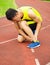 Young male runner with ankle injury on track