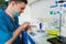 Young male scientist in uniform wearing a mask weighs powder on