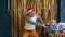 Young male with shopping cart filled of assorted baubles and christmas presents. Man in santa hat and bright glasses