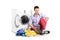 A young male sitting next to a washing machine