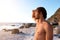 Young male standing at beach looking at water