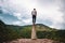 Young male standing on a platform surrounded by hills under a cloudy sky