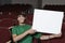 Young Male Student Holding Billboard In Classroom