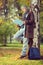 Young male student leaning on a tree and reading a book in a par