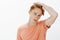 Young male student with red hair and freckles gazing at mirror and touching haircut, thinking to change hairstyle