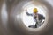 Young male supervisor examining large pipe at construction site