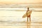 Young male surfer at the beach for sunrise with surfboard