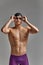 Young male swimmer preparing for the start, close-up portrait of a swimmer in a mask and a hat, gray background, copy